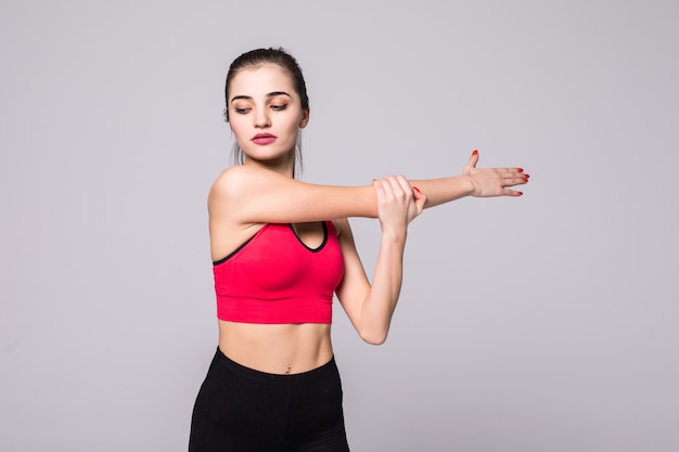 Mujer fitness haciendo ejercicios de estiramiento. Mujer joven en la pared blanca. Estiramiento y motivación