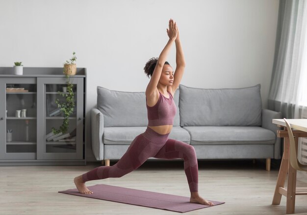 Mujer fitness haciendo yoga en una estera de yoga en casa