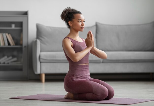 Mujer fitness haciendo yoga en una estera de yoga en casa