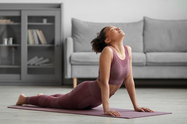 Mujer fitness haciendo yoga en una estera de yoga en casa