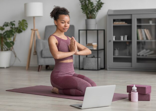 Mujer fitness haciendo yoga en una estera de yoga en casa