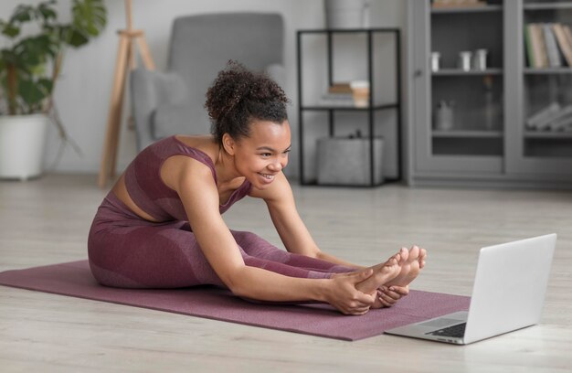 Mujer fitness haciendo yoga en una estera de yoga en casa