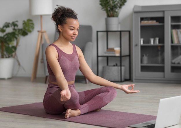 Mujer fitness haciendo yoga en una estera de yoga en casa