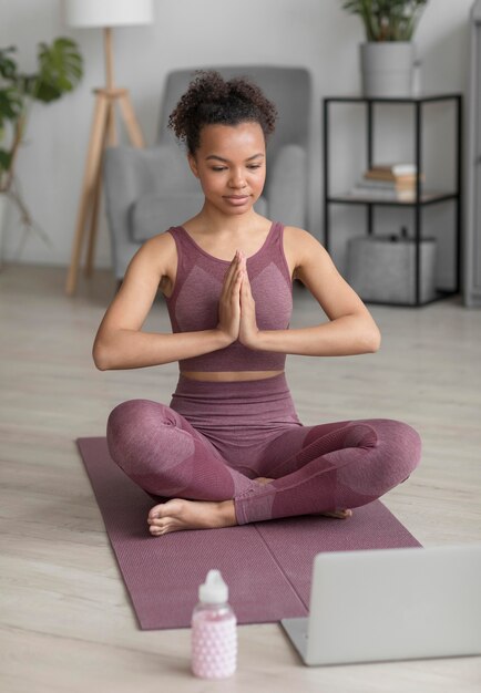 Mujer fitness haciendo yoga en una estera de yoga en casa