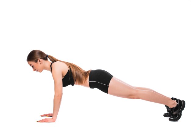 Mujer fitness en postura de plancha básica de entrenamiento de abdominales sobre fondo blanco.