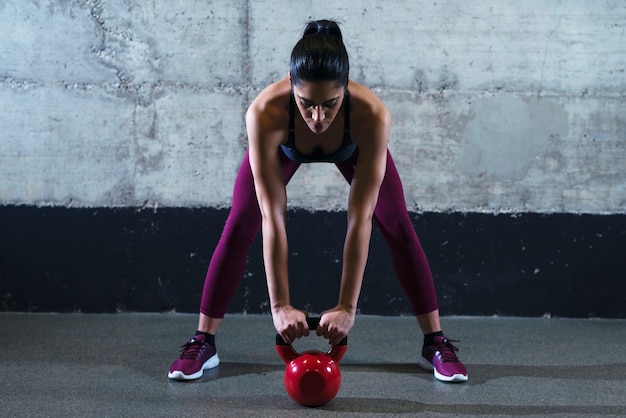 Mujer fitness en ropa deportiva ejercicio con pesas de campana de hervidor en el gimnasio