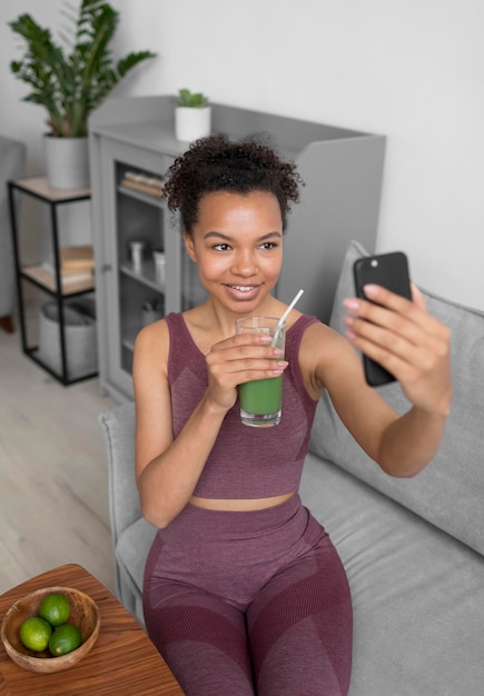 Mujer fitness tomando un selfie mientras toma un jugo de frutas