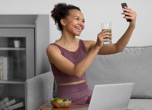Mujer fitness tomando un selfie mientras toma un jugo de frutas