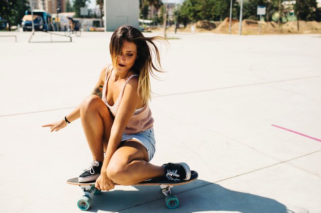 Mujer flexible haciendo un truco con la patineta