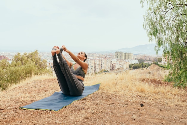 Mujer flexible haciendo yoga al aire libre