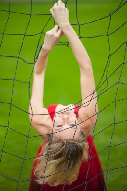 Mujer flexible con vestido rojo agarrando una red