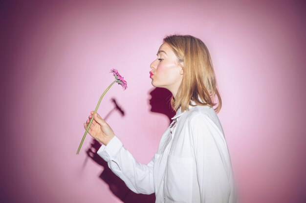 Mujer con flores gerbera haciendo pucheros en los labios.