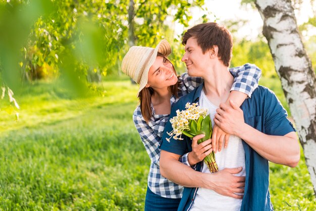 Mujer con flores de nuevo abrazando hombre guapo