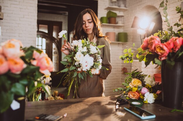 Mujer florista en su propia tienda de flores cuidando flores