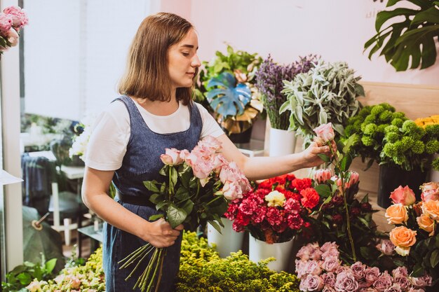 Mujer florista en su propia tienda de flores cuidando flores