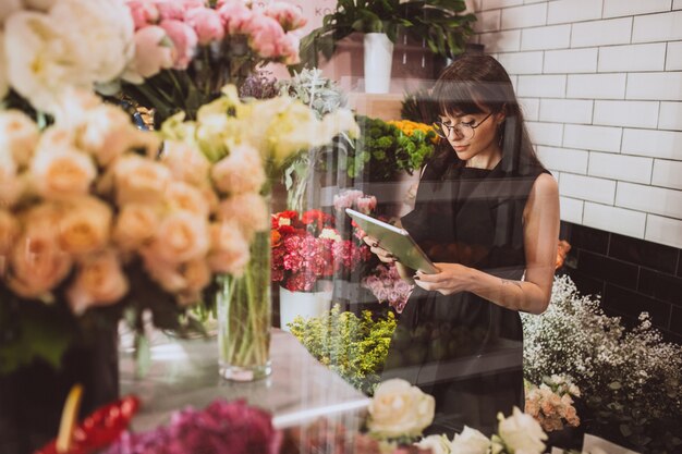 Mujer florista en su propia tienda de flores cuidando flores