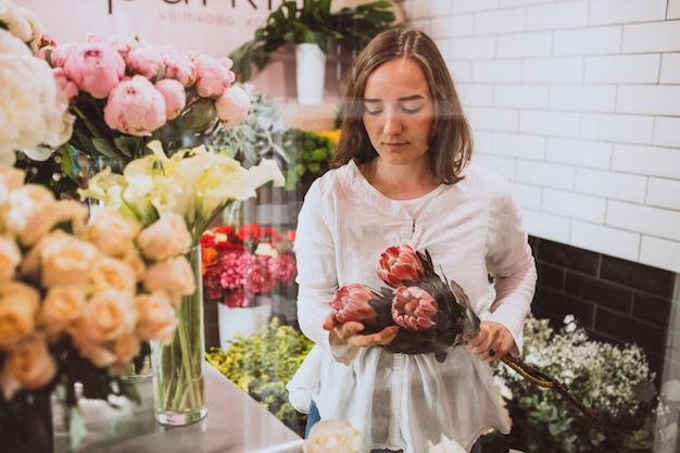 Mujer florista en su propia tienda de flores cuidando flores