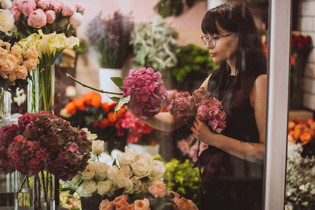 Mujer florista en su propia tienda de flores cuidando flores