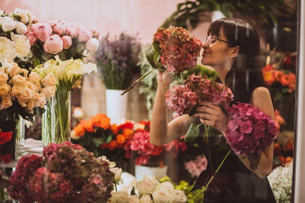 Mujer florista en su propia tienda de flores cuidando flores