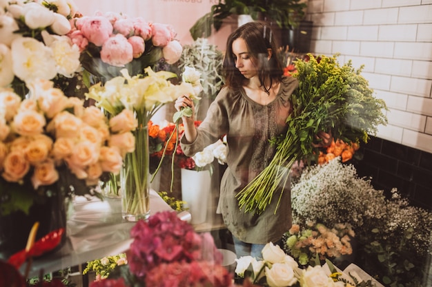 Mujer florista en su propia tienda de flores cuidando flores