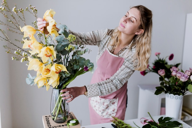 Mujer de floristería tomando flores amarillas