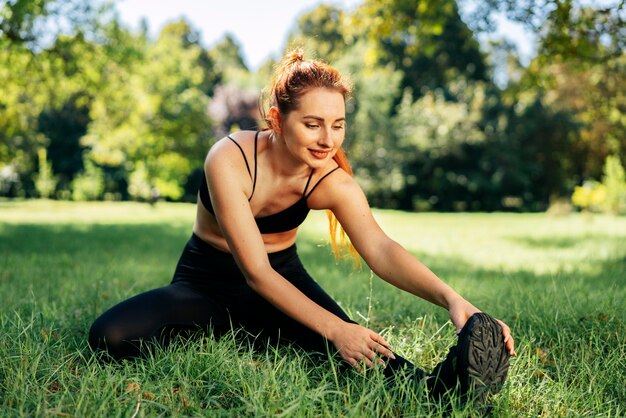 Mujer en forma de disparo completo haciendo ejercicio sobre el césped