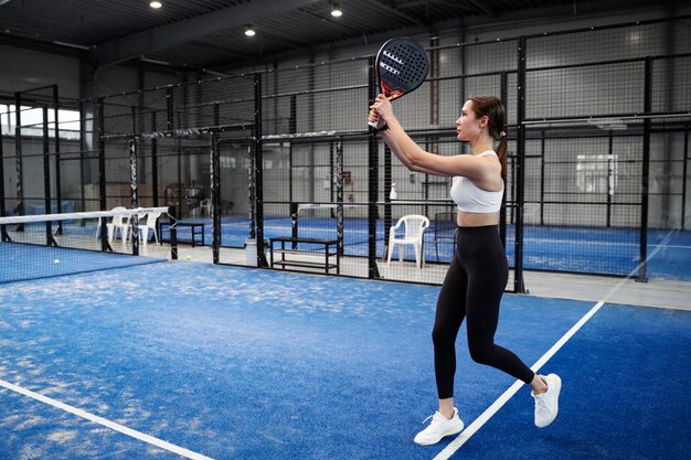 Mujer en forma jugando al pádel tiro completo