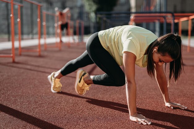 Mujer en forma con ropa deportiva entrenando abdominales en el estadio de la ciudad