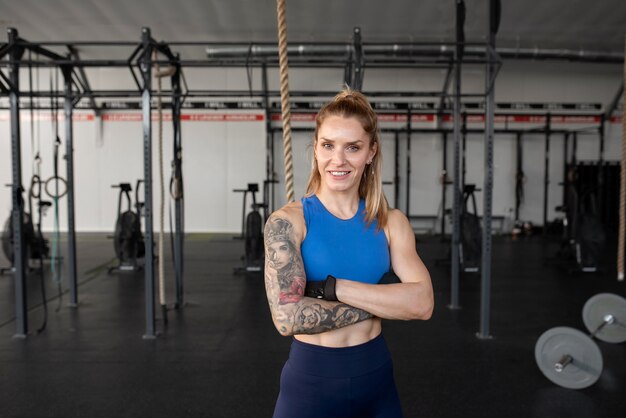 Mujer en forma sonriente de tiro medio en el gimnasio