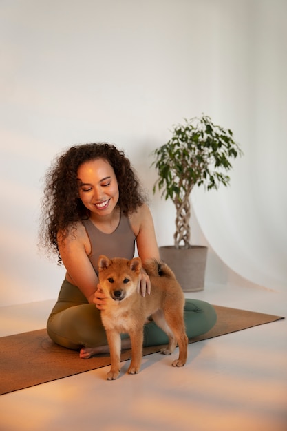 Mujer en forma de tiro completo haciendo deporte con perro en el interior