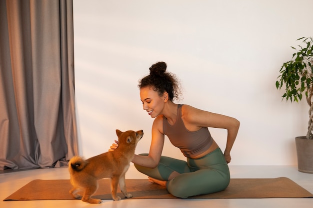 Foto gratuita mujer en forma de tiro completo haciendo deporte con perro en el interior