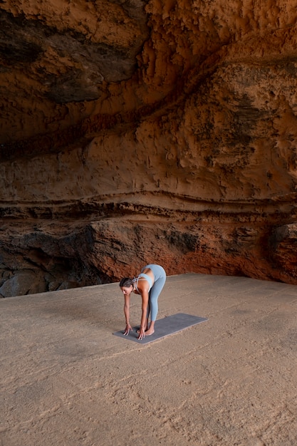 Mujer en forma de tiro largo haciendo yoga al aire libre