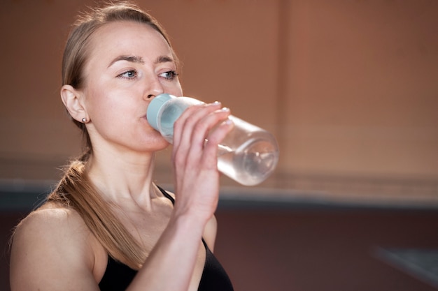 Foto gratuita mujer en forma de tiro medio bebiendo agua