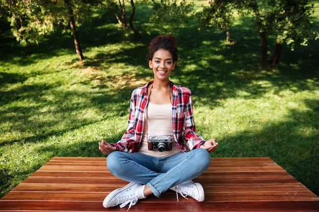 Foto gratuita mujer fotógrafa sentada al aire libre en el parque meditar