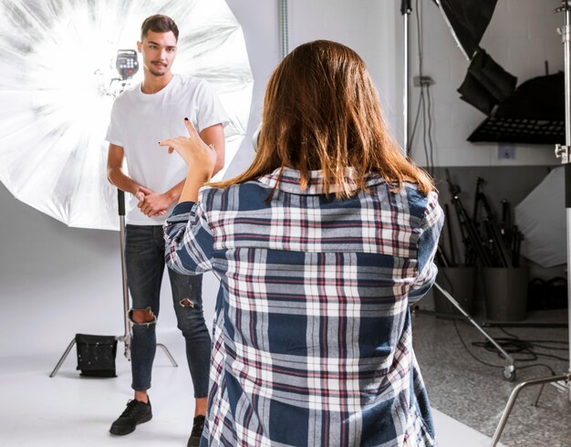 Mujer fotógrafa tomando una foto de modelo masculino