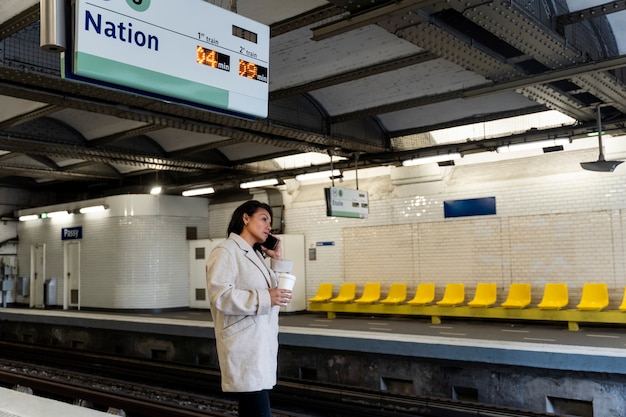 Mujer francesa esperando el metro y bebiendo café