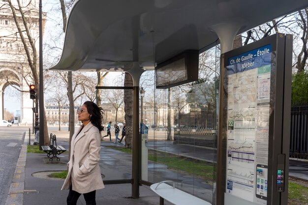 Mujer francesa joven que espera en la estación para el autobús