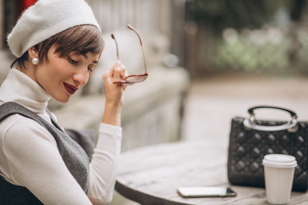 Foto gratuita mujer francesa tomando café en la cafetería en la terraza