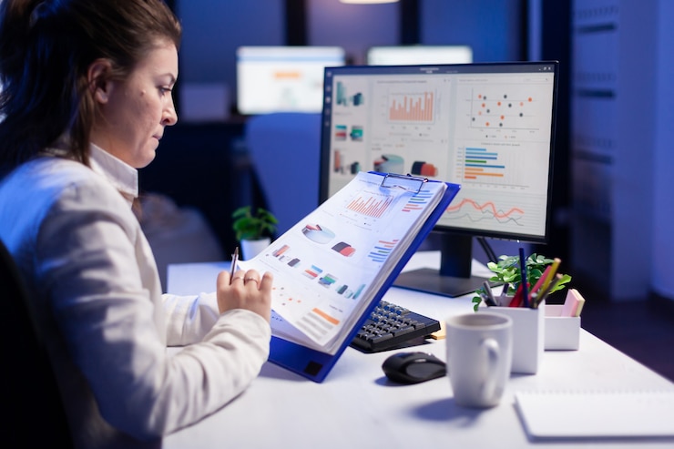 Foto gratuito mujer freelance comparando gráficos de la pizarra con gráficos de computadora en una oficina de negocios