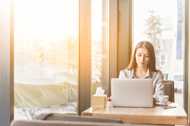 Mujer freelance trabajando con portátil en cafetería