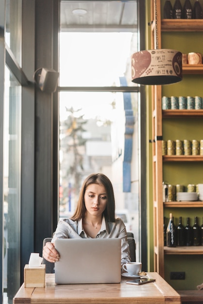 Foto gratuita mujer freelance trabajando con portátil en cafetería