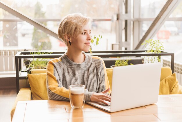 Foto gratuita mujer freelance trabajando con portátil en cafetería