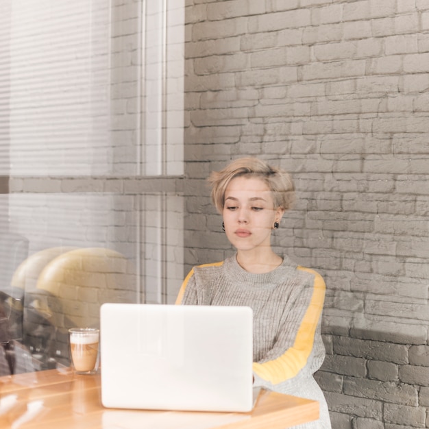 Foto gratuita mujer freelance trabajando con portátil en cafetería