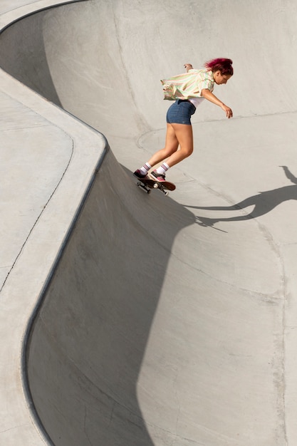 Mujer fresca de tiro completo divirtiéndose en patineta