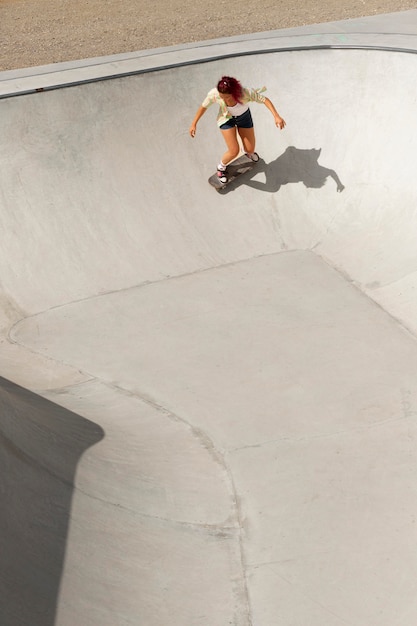 Mujer fresca de tiro largo divirtiéndose en patineta