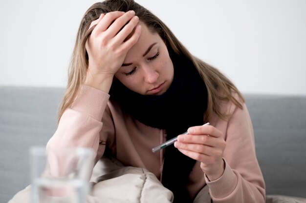 Mujer con frío comprobando el termómetro