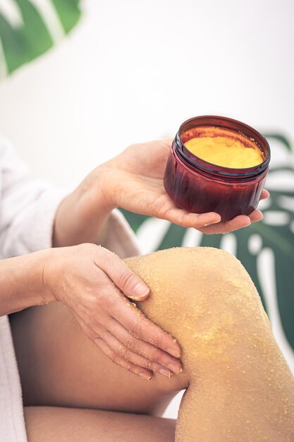 Una mujer se frota el cuerpo con un exfoliante corporal.