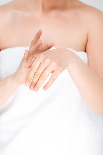 Mujer frotando crema en las manos, use toalla