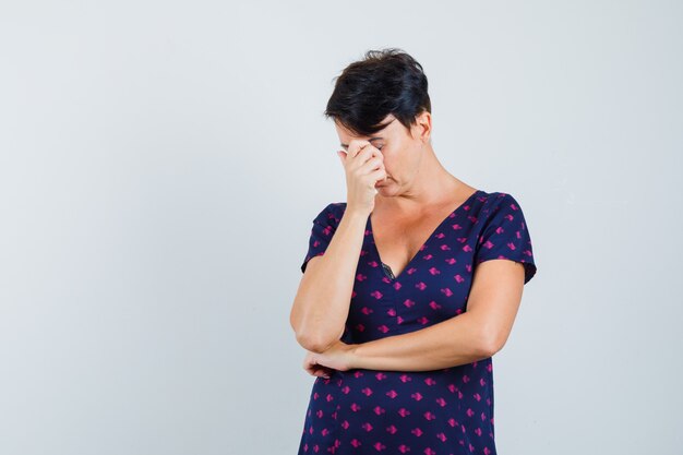 Mujer frotándose los ojos y la nariz en el vestido y con aspecto cansado.