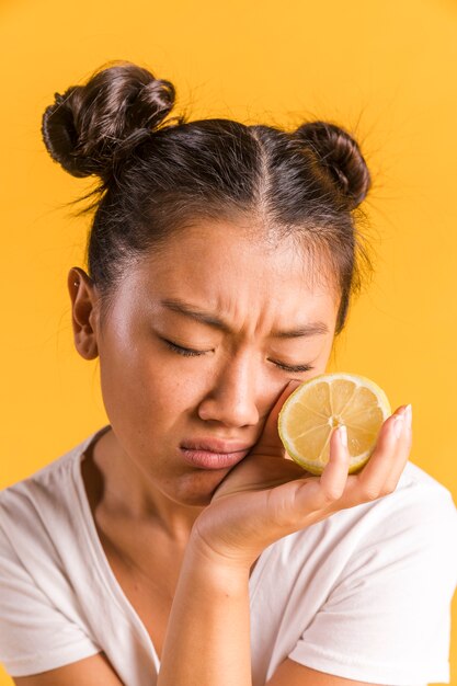 Mujer frunciendo el ceño y sosteniendo un limón